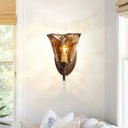 Beside a sunny window and a pile of white pillows, this Clérachic wall sconce glows through its amber glass, casting a sparkle on the wall.