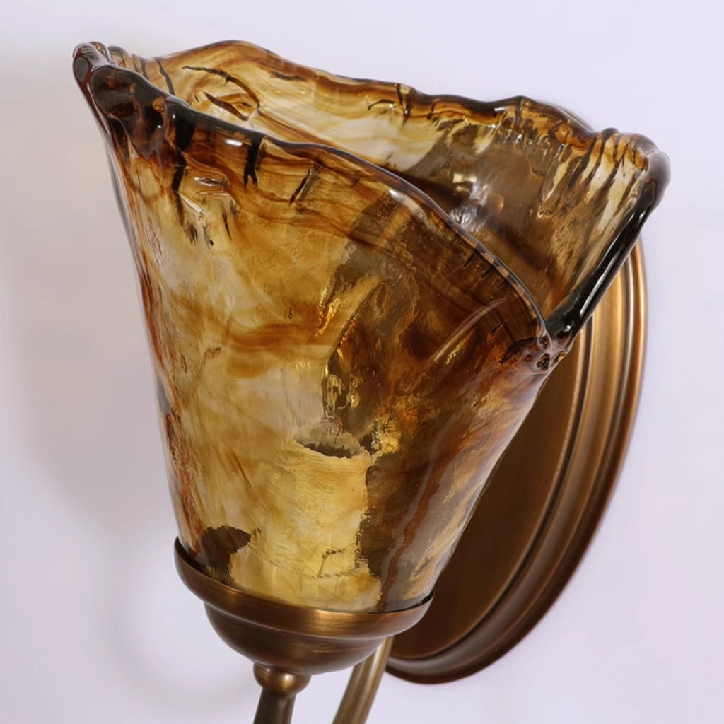 Close view of the swirled amber and dark brown streaks in the wavy glass shade of this Clérachic wall sconce.