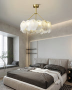 The Clérachic Cryon over a made bed in a soft beige bedroom, alabaster tiers catching the window daylight.