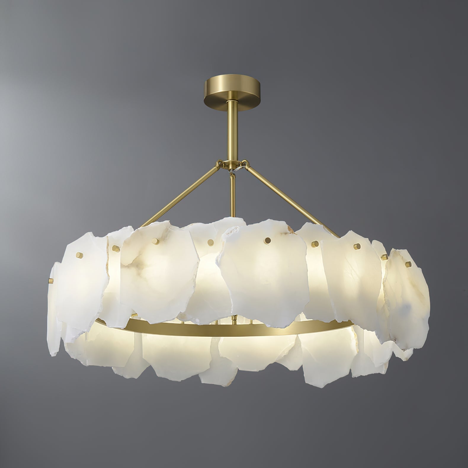The Clérachic Cryon lit on grey, warm light spilling from the brushed brass band beneath the stone petals.