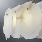The Clérachic Cryon in macro, its raw-edged alabaster plates translucent and fixed with slim brass studs.