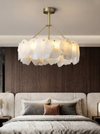 Clérachic Cryon lit above a wide upholstered bed, set against a dark timber wall in a calm bedroom.