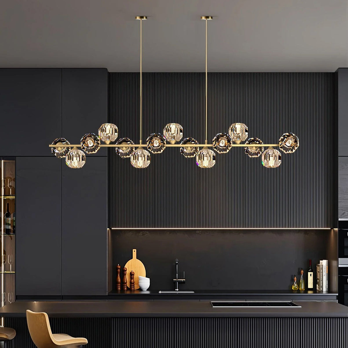 This Clérachic chandelier hangs from two thin rods in a dark fluted kitchen, its crystal balls glowing above a bar with a tan stool.