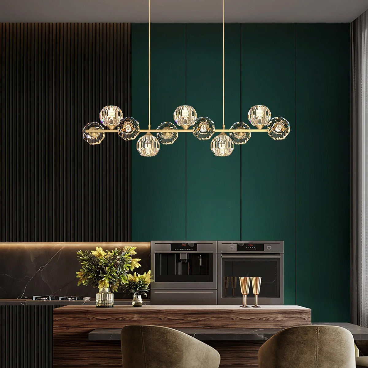 A long brass bar of crystal balls over a walnut kitchen island, a Clérachic chandelier set against deep green cabinets.