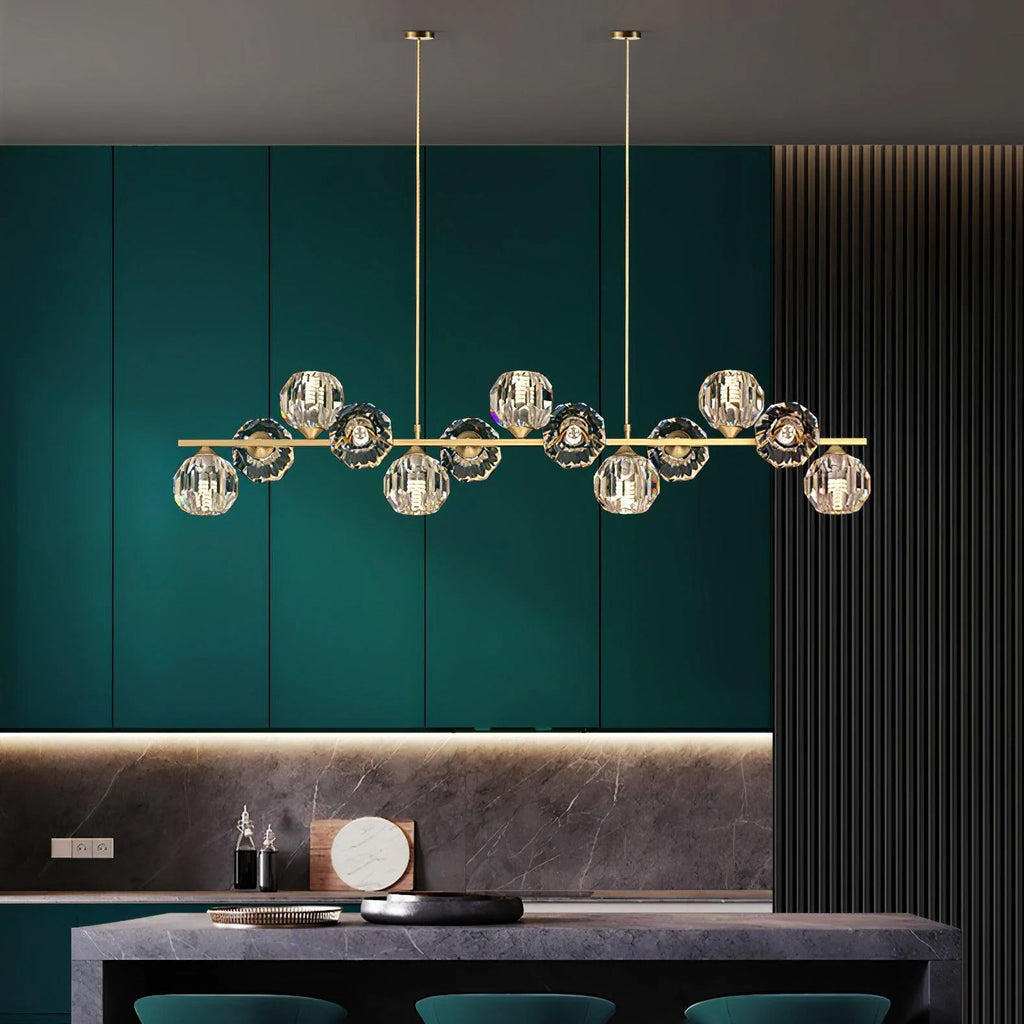 Crystal-ball chandelier in brass against teal cabinets, a dark stone counter below, from Clérachic.