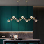Crystal-ball chandelier in brass against teal cabinets, a dark stone counter below, from Clérachic.