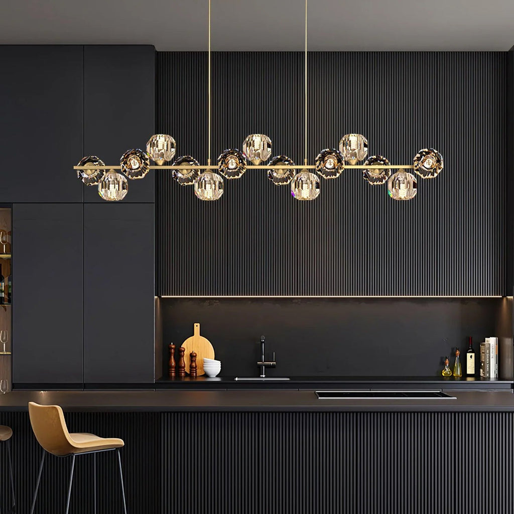 Wider view of the Clérachic chandelier in a charcoal kitchen, the brass bar and crystal balls centred above the worktop.