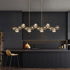 Close to the ceiling in a dark kitchen, a Clérachic chandelier hangs on long rods over a fluted island with a stool.
