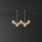 Short brass bar with crystal balls and two straight rods against a grey wall, a Clérachic chandelier.