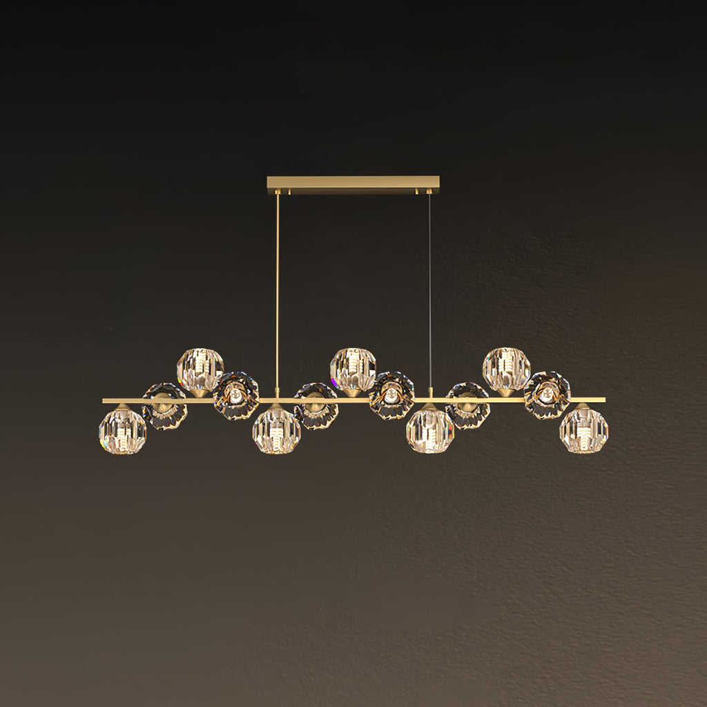 This Clérachic chandelier uses a rectangular brass canopy with two drop cords, its crystal balls lit warm against a brown backdrop.
