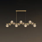 This Clérachic chandelier uses a rectangular brass canopy with two drop cords, its crystal balls lit warm against a brown backdrop.