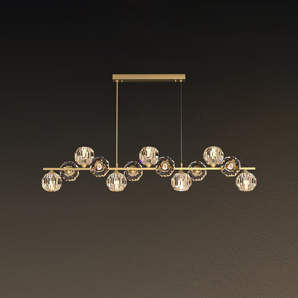 This Clérachic chandelier uses a rectangular brass canopy with two drop cords, its crystal balls lit warm against a brown backdrop.