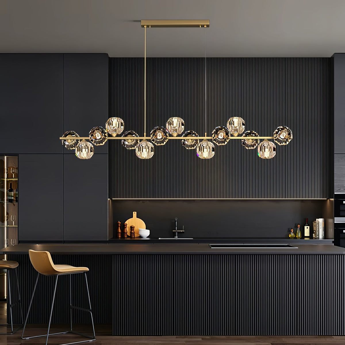 A rectangular canopy holds this Clérachic chandelier over a dark fluted kitchen island, brass bar and crystal balls lit.