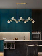 A Clérachic chandelier on a rectangular canopy in a teal kitchen with a stone backsplash, oven and white stools.