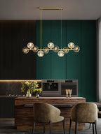 Brass bar of crystal balls over a walnut island, two olive chairs below, a Clérachic chandelier in a green and charcoal room.