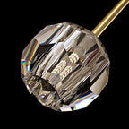 Close view of one faceted crystal ball with a bulb inside, hanging from the brass bar of this Clérachic chandelier.