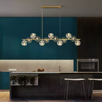 Wide kitchen shot of this Clérachic chandelier over a dark island, teal cabinets and an oven behind it.