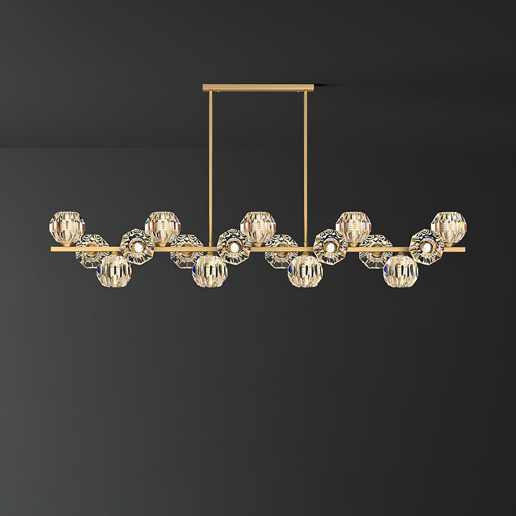 Long brass bar with many clear crystal balls on a rectangular canopy, a Clérachic chandelier against a dark grey wall.
