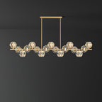 Long brass bar with many clear crystal balls on a rectangular canopy, a Clérachic chandelier against a dark grey wall.