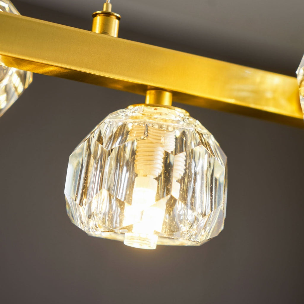 Close view of a lit crystal ball under the brass bar on this Clérachic chandelier, with its screw-in bulb visible.