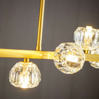 Close view of two lit crystal balls and the rod meeting the brass bar on this Clérachic chandelier.