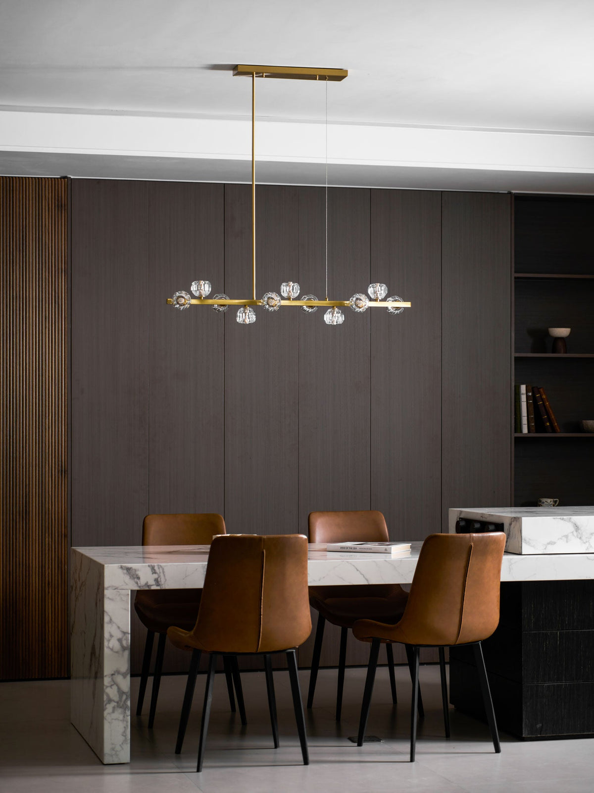 Tall room shot: this Clérachic chandelier hangs low above a marble dining table with four black-legged leather chairs.