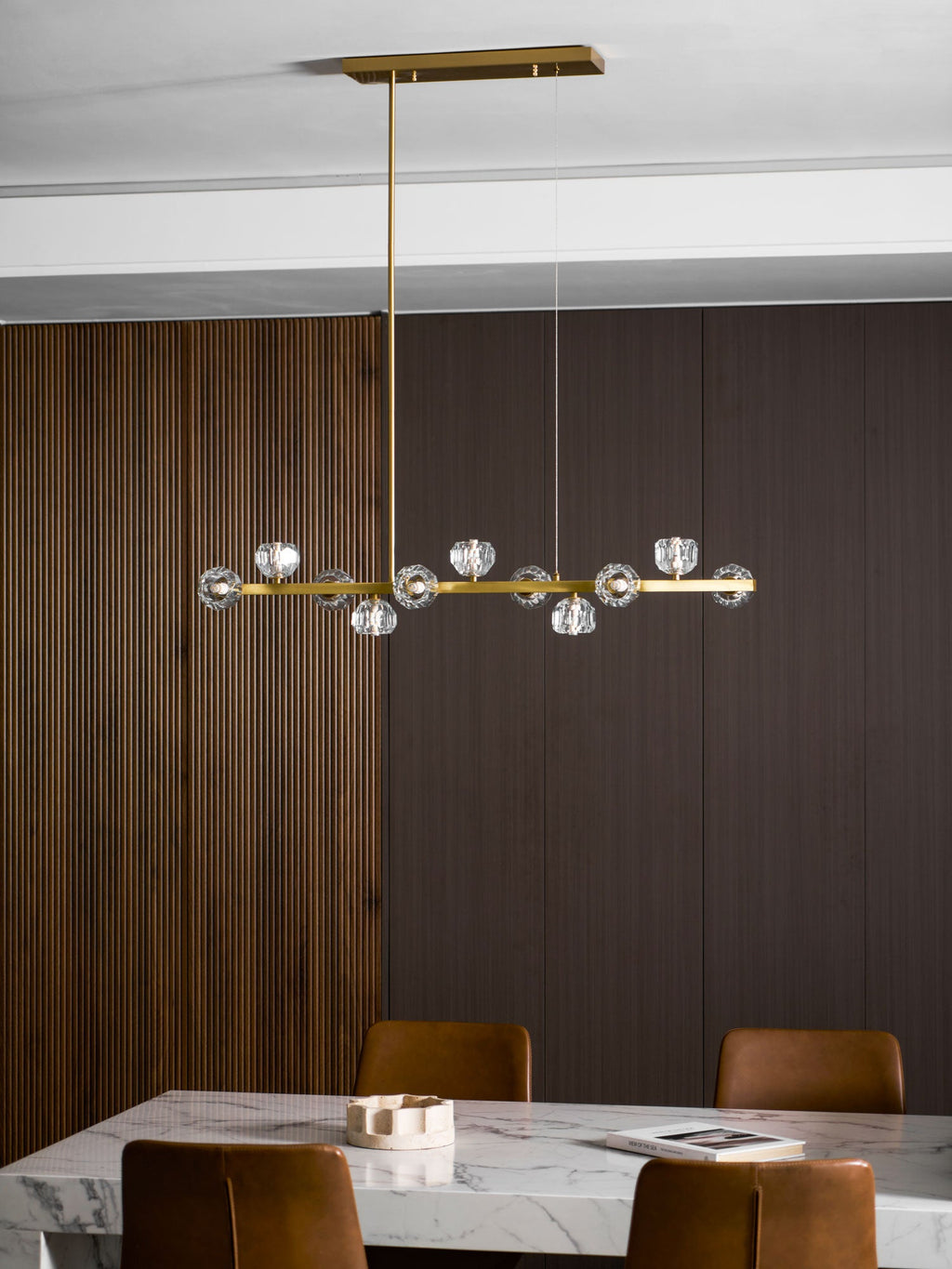 Clérachic chandelier on a rectangular canopy above a marble table, ribbed wood panelling on one side.