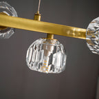 Close view of a crystal ball and bulb beneath a flat brass bar, with a twisted cord above, on this Clérachic chandelier.