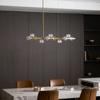 Wide view of this Clérachic chandelier over a marble table, with a bookshelf and a dark wood wall at the back.