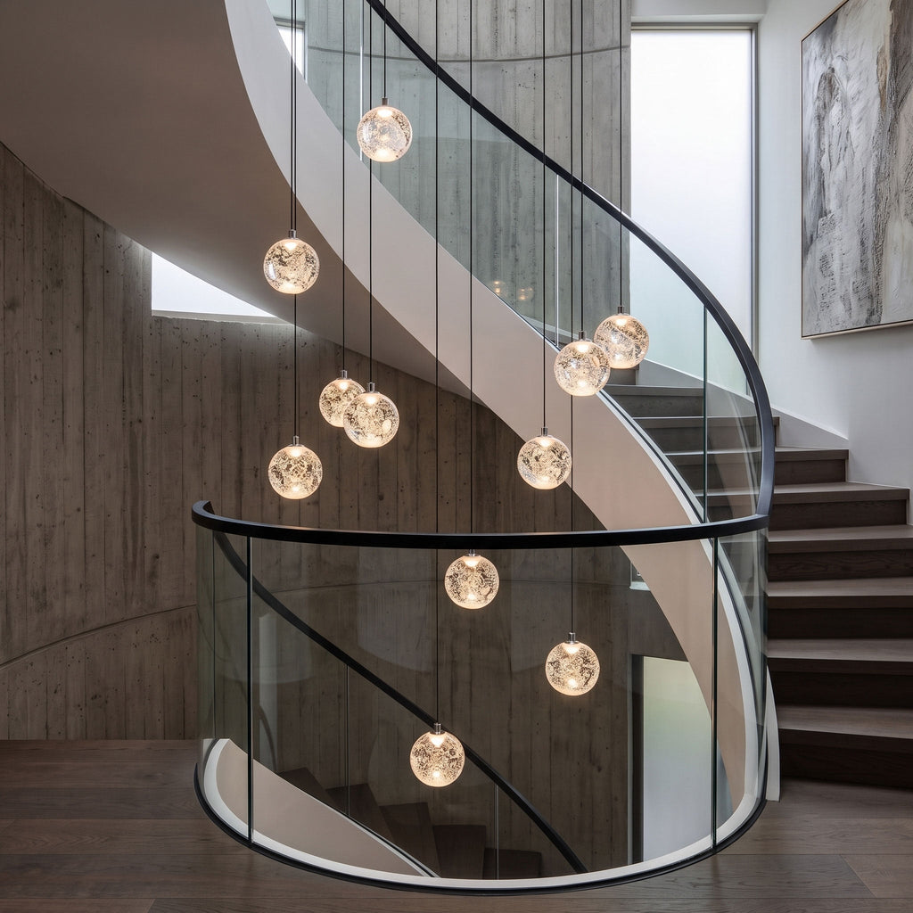Clérachic crystal ball pendants hung at different heights in a concrete stairwell with a curved glass balustrade.