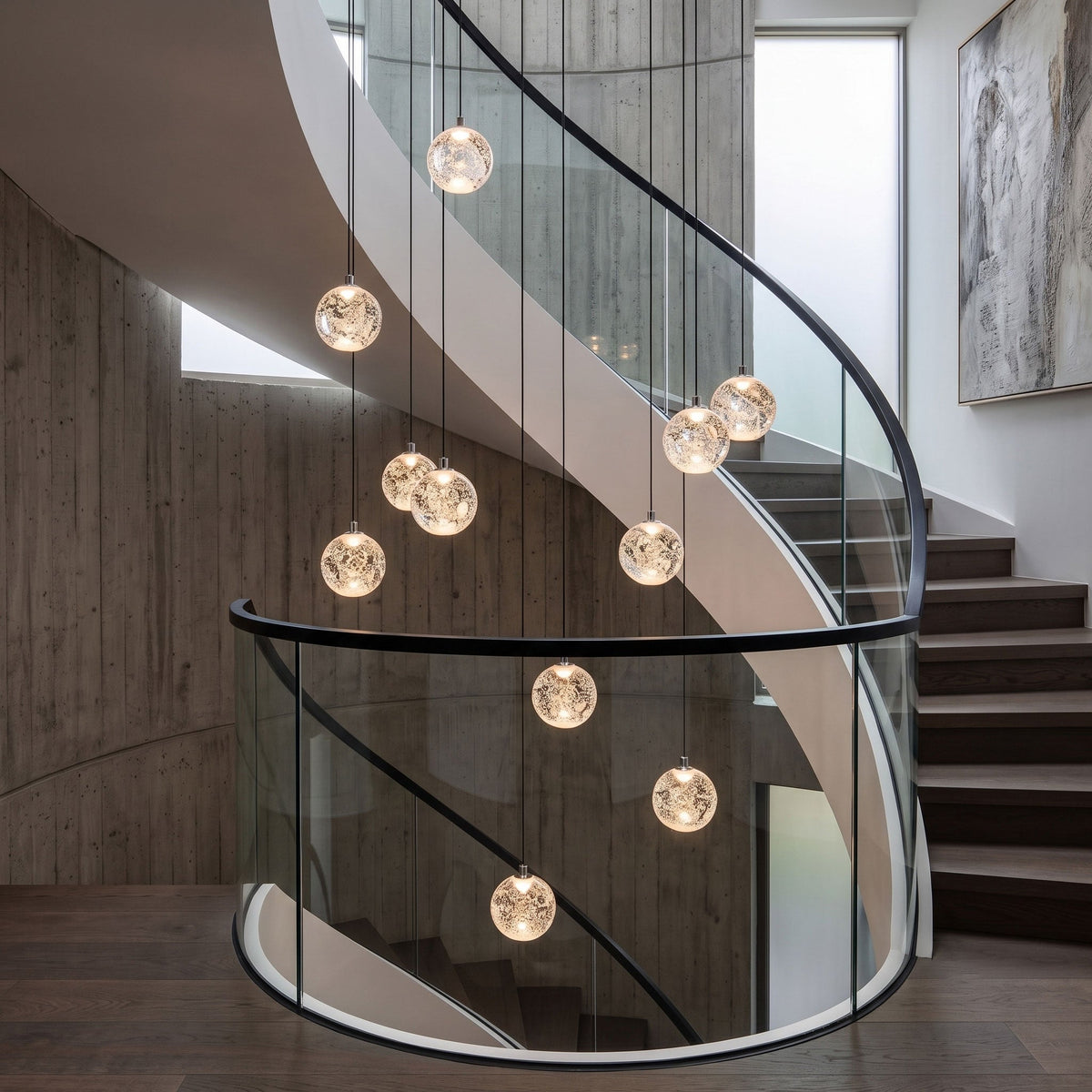 Clérachic crystal ball pendants hung at different heights in a concrete stairwell with a curved glass balustrade.