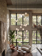 Clérachic crystal ball pendants dropping past tall black-framed windows over a cream sofa and a low table in a double-height room.
