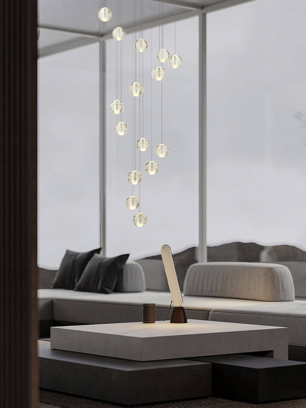 Clérachic crystal ball pendants in a slim spiral through a tall glazed room, above a grey sofa and a low table.