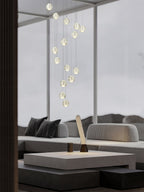 Clérachic crystal ball pendants in a slim spiral through a tall glazed room, above a grey sofa and a low table.