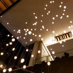 Looking up at a canopy of Clérachic crystal balls glowing against a dark ceiling, with a long landing beyond.
