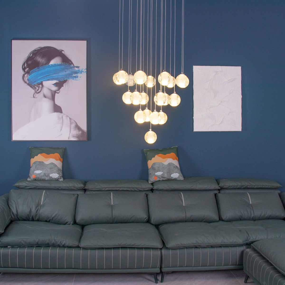 A glowing triangle of Clérachic crystal balls on a teal wall above a green leather sofa, with a framed print and a white panel.