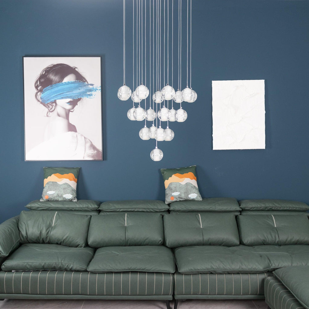 The same Clérachic crystal ball cluster switched off, the clear spheres pale against a teal wall above a green leather sofa.
