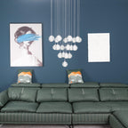 The same Clérachic crystal ball cluster switched off, the clear spheres pale against a teal wall above a green leather sofa.