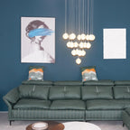 Wider view of the glowing Clérachic crystal ball cluster hung above a green leather sofa, with a framed print and a white panel.