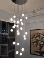 Clérachic crystal ball pendants glowing in a tall room with a round ceiling plate, a framed floral painting and a dark window.