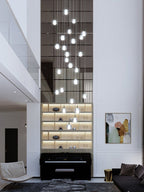 A long spiral of Clérachic crystal balls glowing down a double-height wall of mirrored panels, above a piano and lit shelves.