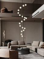 A single slim spiral of Clérachic crystal balls hanging in a double-height living room, above a curved sofa and a low round table.