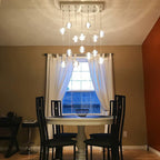 A rectangular canopy with Clérachic crystal balls glowing at different heights over a round dining table and black chairs.