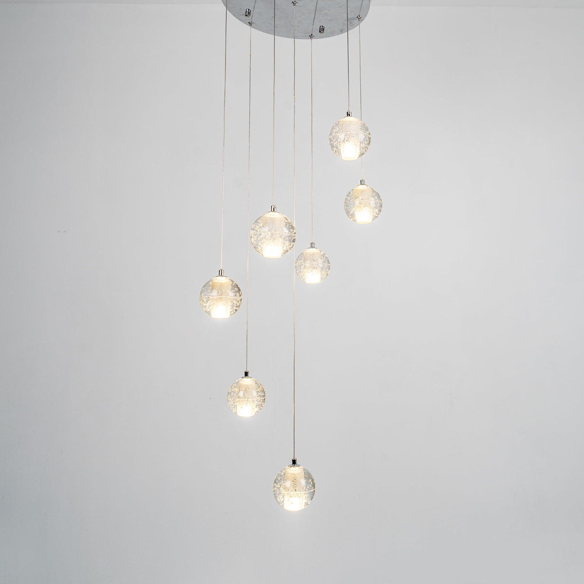 The Clérachic crystal ball pendants lit warm on grey, shown from a slightly different angle below the chrome ceiling plate.
