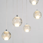 Close view of lit Clérachic crystal balls, their bubbled glass glowing around frosted inner cores with chrome caps.