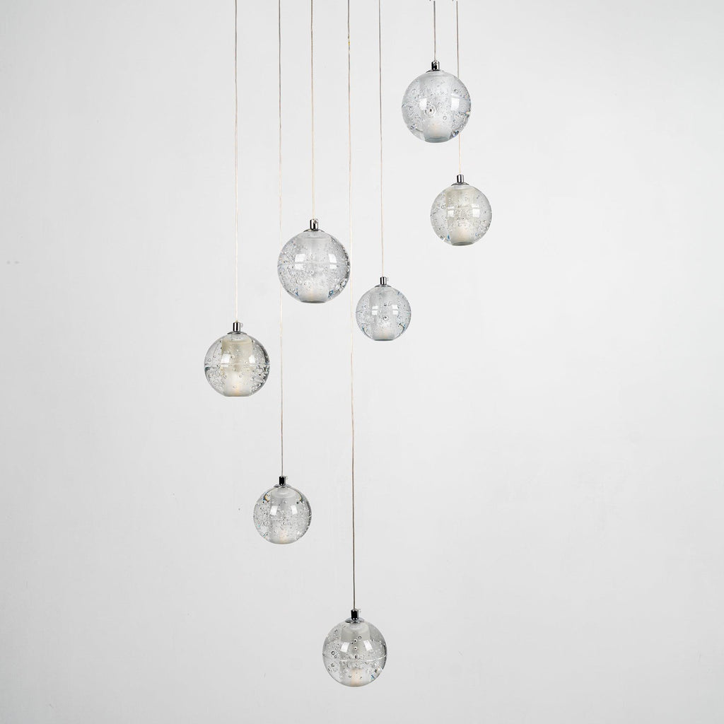 Clérachic crystal ball pendants unlit against pale grey, the clear bubbled spheres hanging at different heights on thin cables.