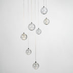 Clérachic crystal ball pendants unlit against pale grey, the clear bubbled spheres hanging at different heights on thin cables.