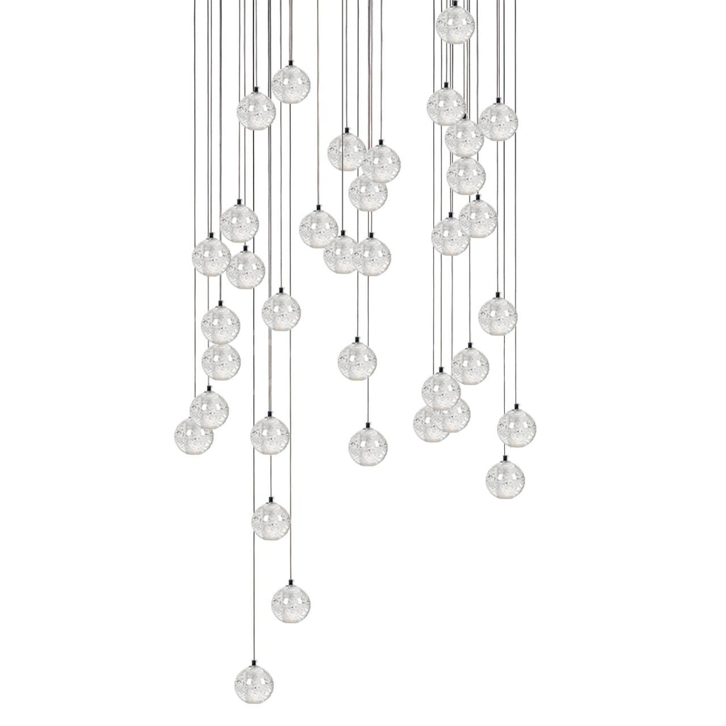 A broad cluster of Clérachic crystal ball pendants with the spheres overlapping at several heights on thin cables, on white.