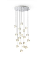 Clérachic crystal ball pendants lit warm below a round chrome ceiling plate, the glowing spheres hanging at staggered heights on white.