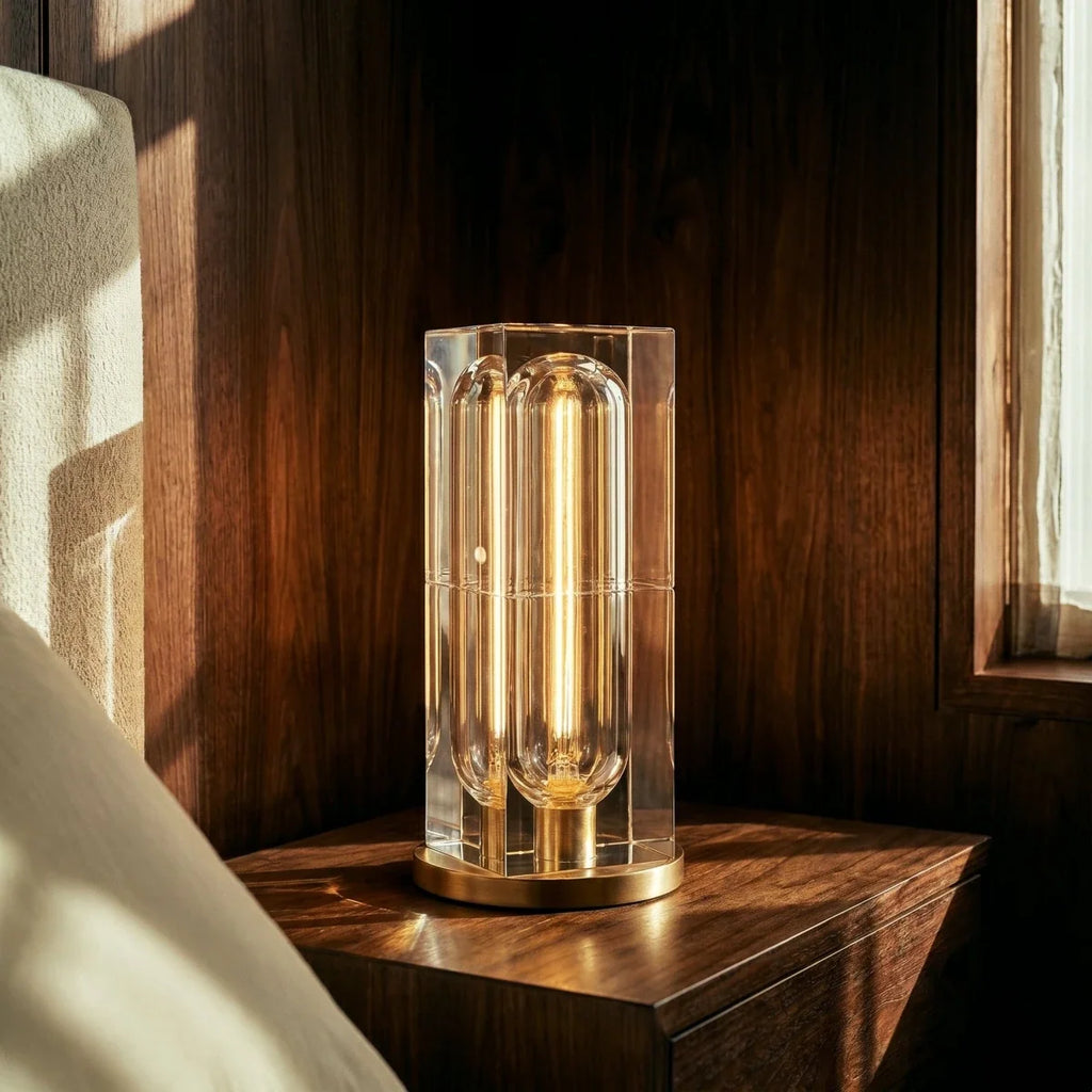 Clérachic tall crystal table lamp with a gold-tone base on a walnut bedside table, lit warm in low evening sun.